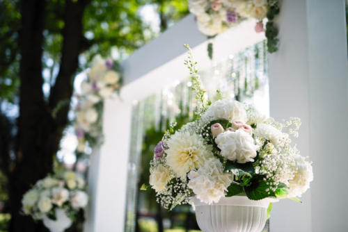 a large vase of flowers stands in nature, lush white colors in a